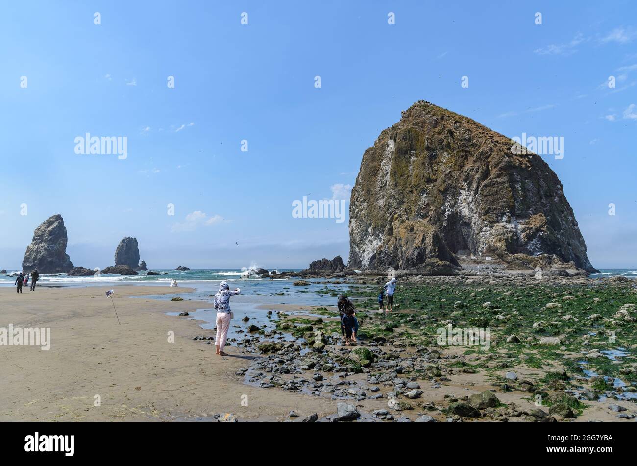 Family with small kid playing in front of Haystack Rock at the Cannon Beach, Oregon, USA. Stock Photo