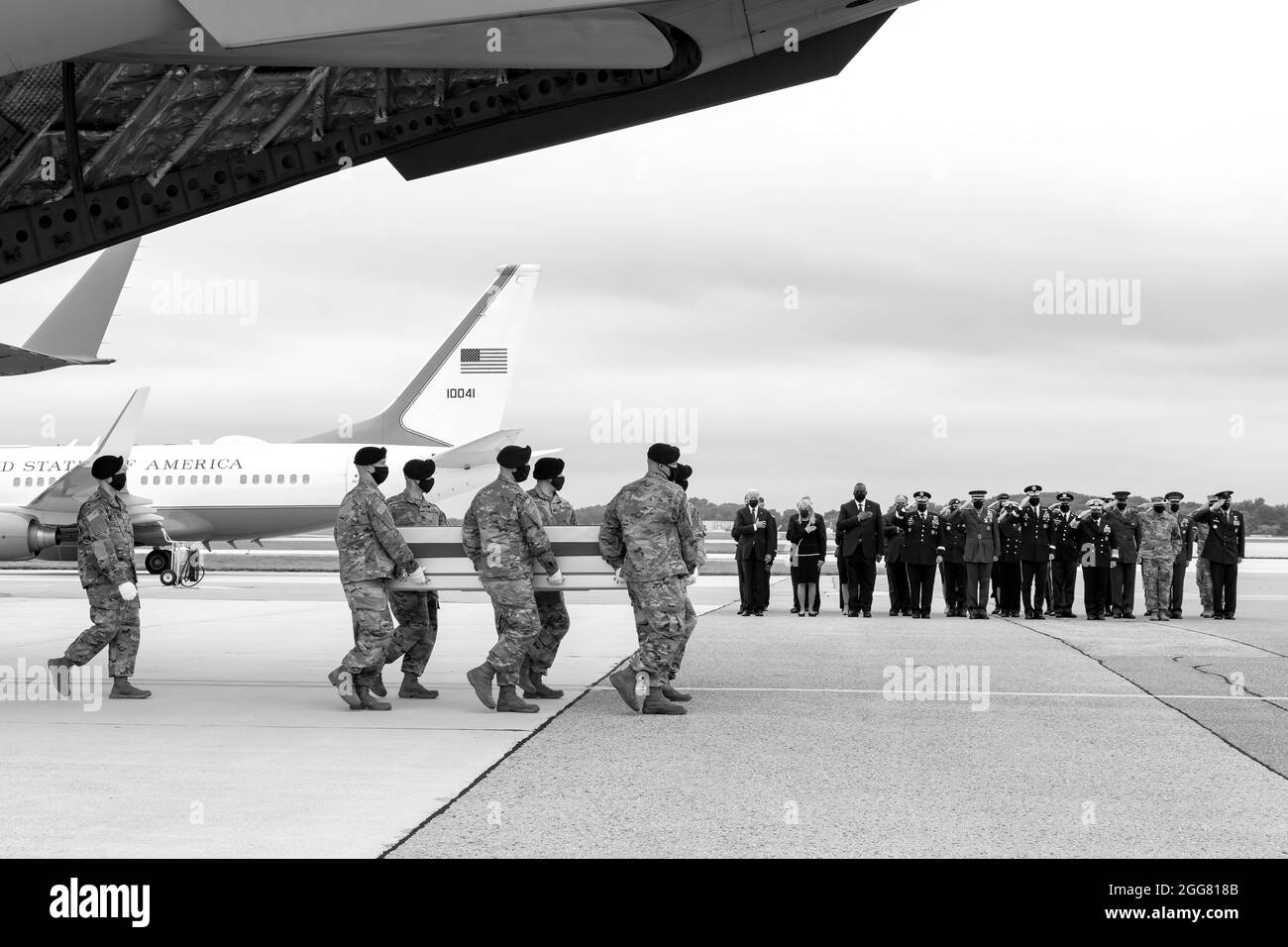 A U.S. Army carry team transfers the remains of Army Staff Sgt. Ryan C. Knauss of Corryton, Tennessee, Aug. 29, 2021 at Dover Air Force Base, Delaware. Knauss was assigned to the 9th Psychological Operations Battalion, 8th Psychological Operations Group, Ft. Bragg, North Carolina.President and Mrs. Biden along with Secretary of Defense Austin stand with hands over their hearts. (U.S. Air Force photo by Jason Minto) Stock Photo