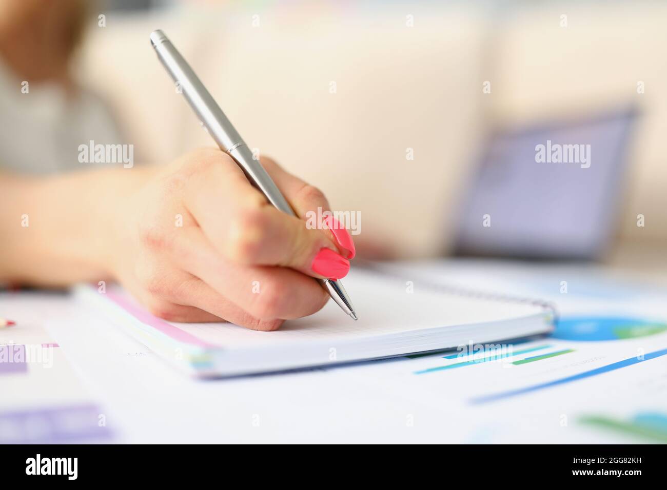 Womans hand taking notes with silver pen close-up Stock Photo