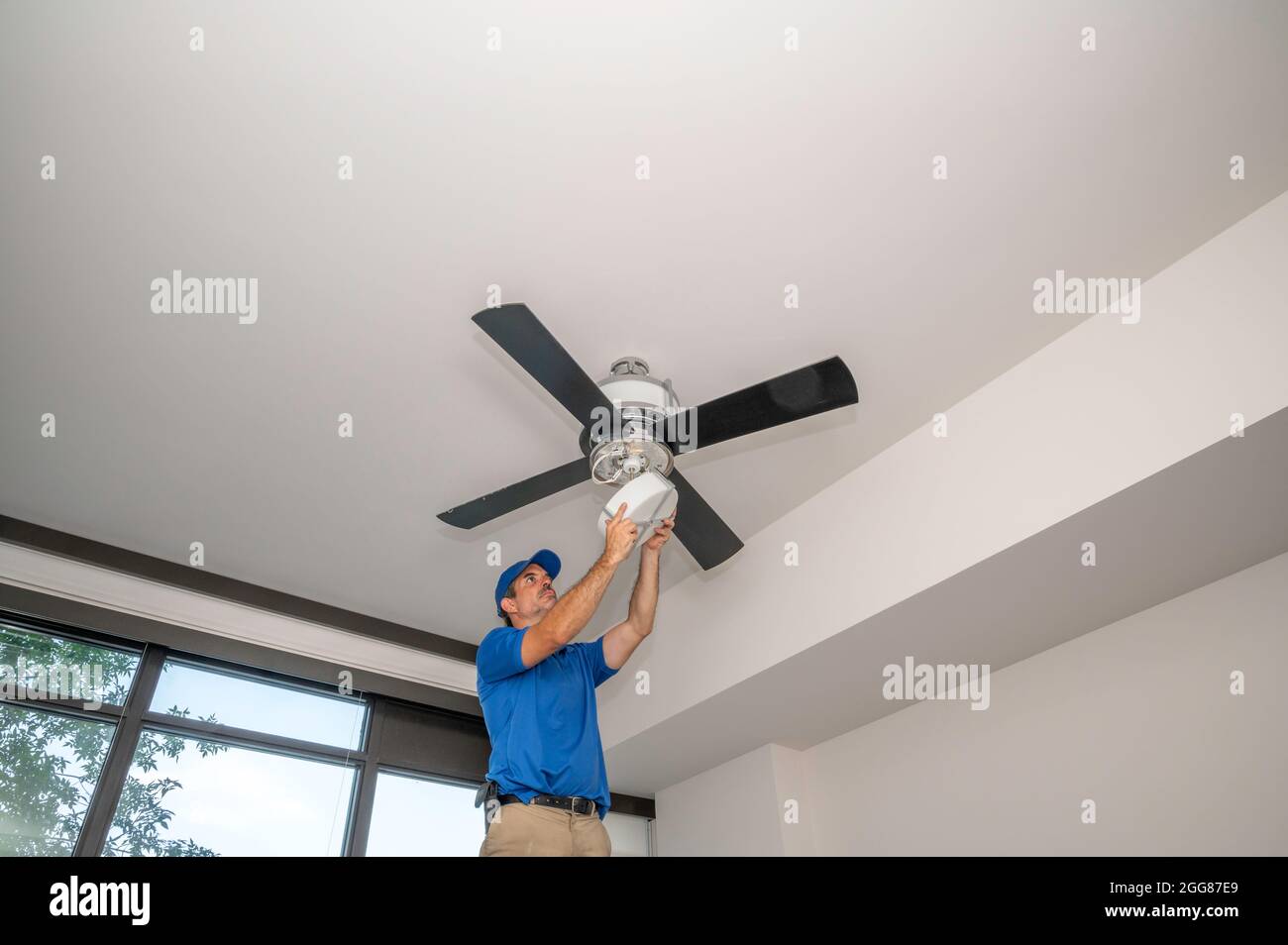 Handyman on ladder working on a ceiling fan Stock Photo Alamy