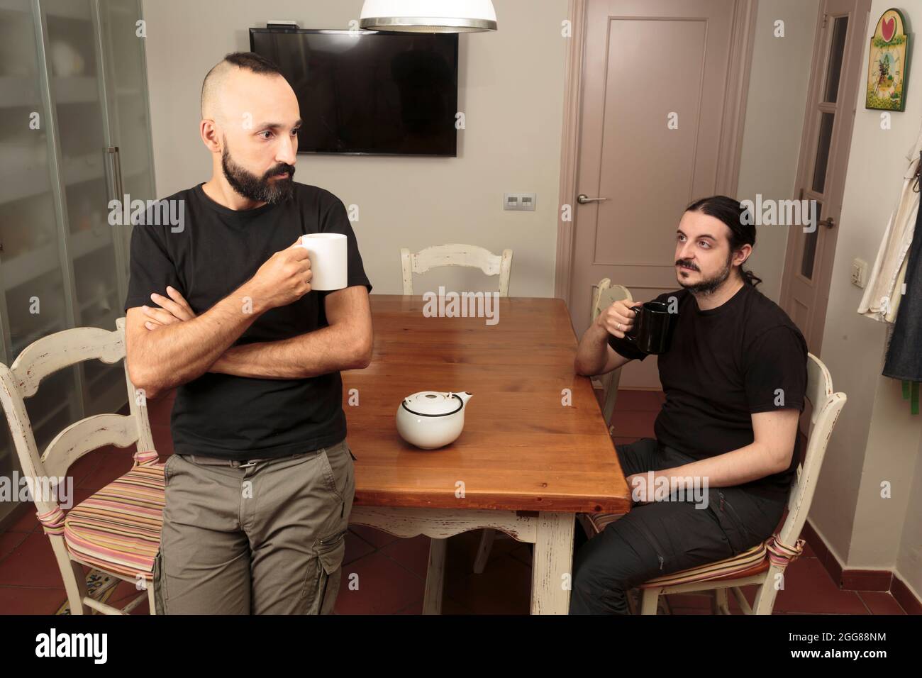 Two young men quietly drinking a hot beverage together Stock Photo