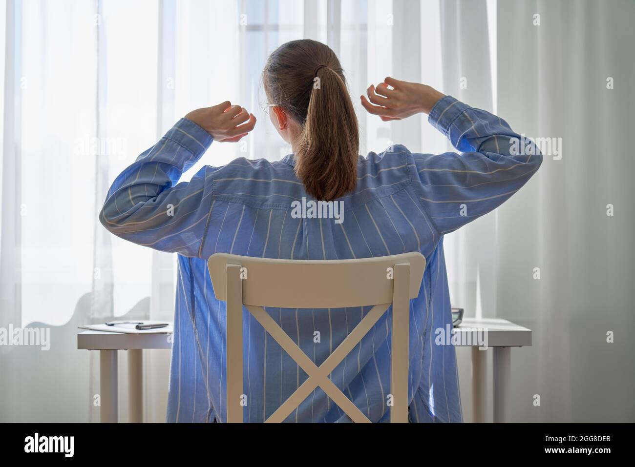 Unrecognizable woman stretching after long-hours working from home. Remote work difficulties Stock Photo