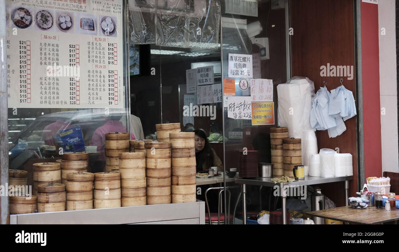 Female siting eating Dim Sum Cantonese cuisine Least affluent neighborhood Sham Shui Po Market Kowloon Hong Kong Stock Photo
