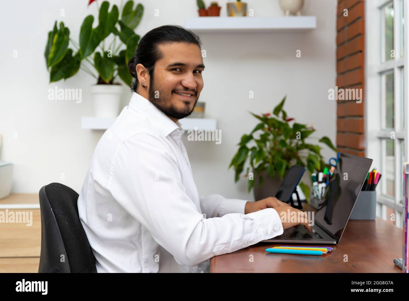 Young latina man using laptop and looking at camera Stock Photo