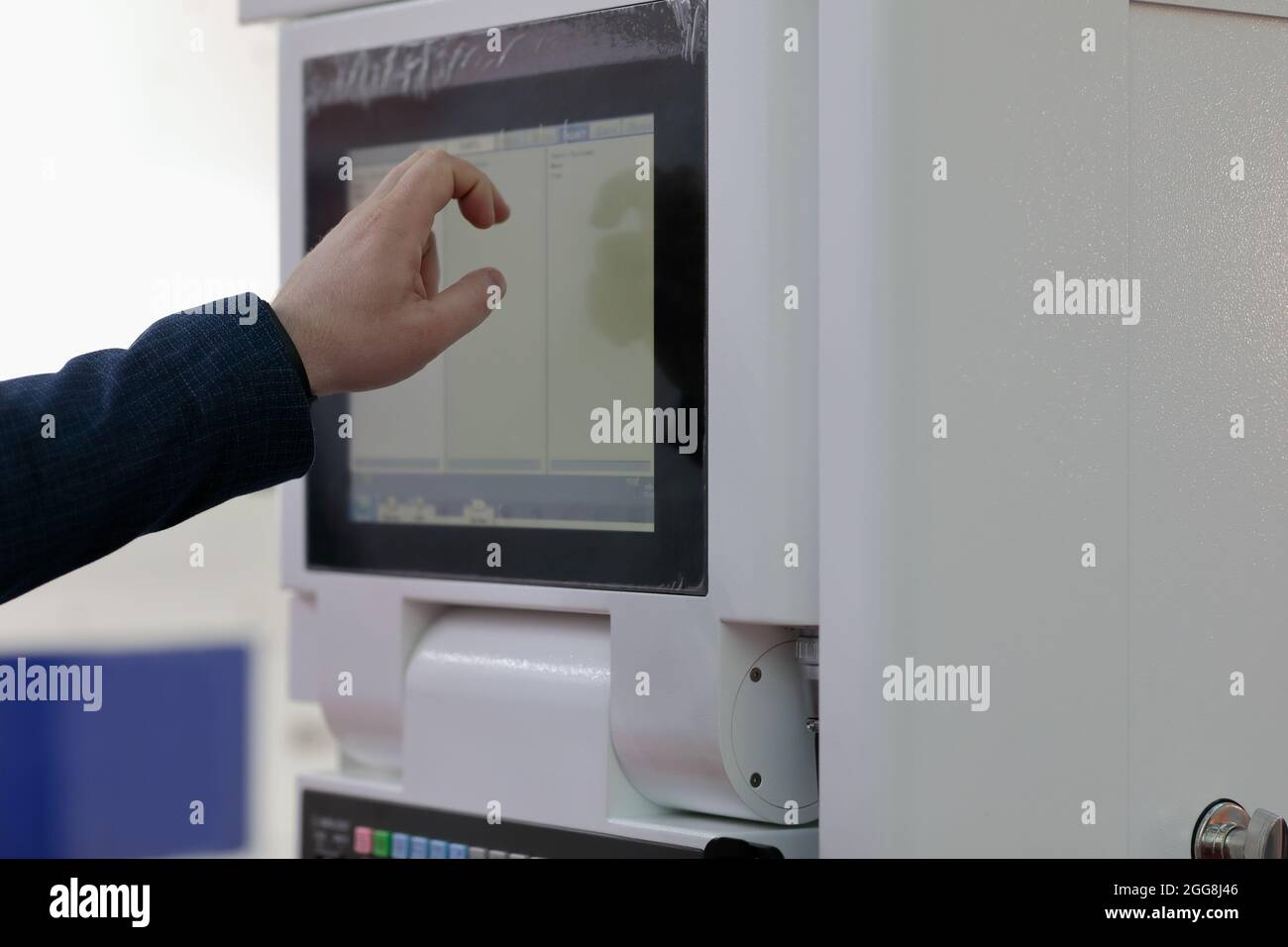 Engineer controls modern industrial equipment by touchscreen. Selective focus. Stock Photo