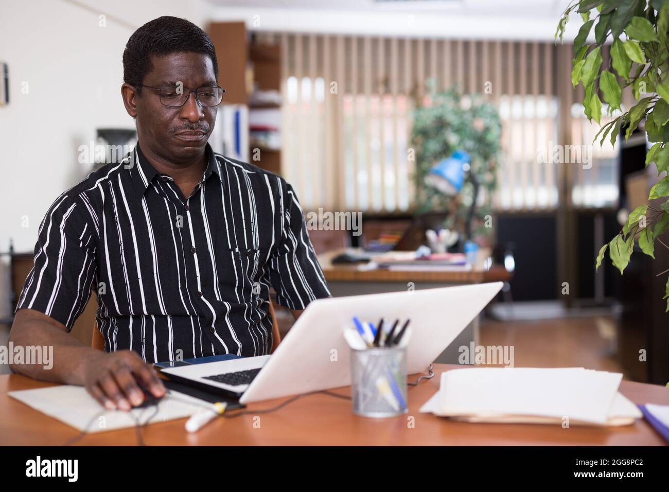 Focused african american man types documentation on a computer in the ...