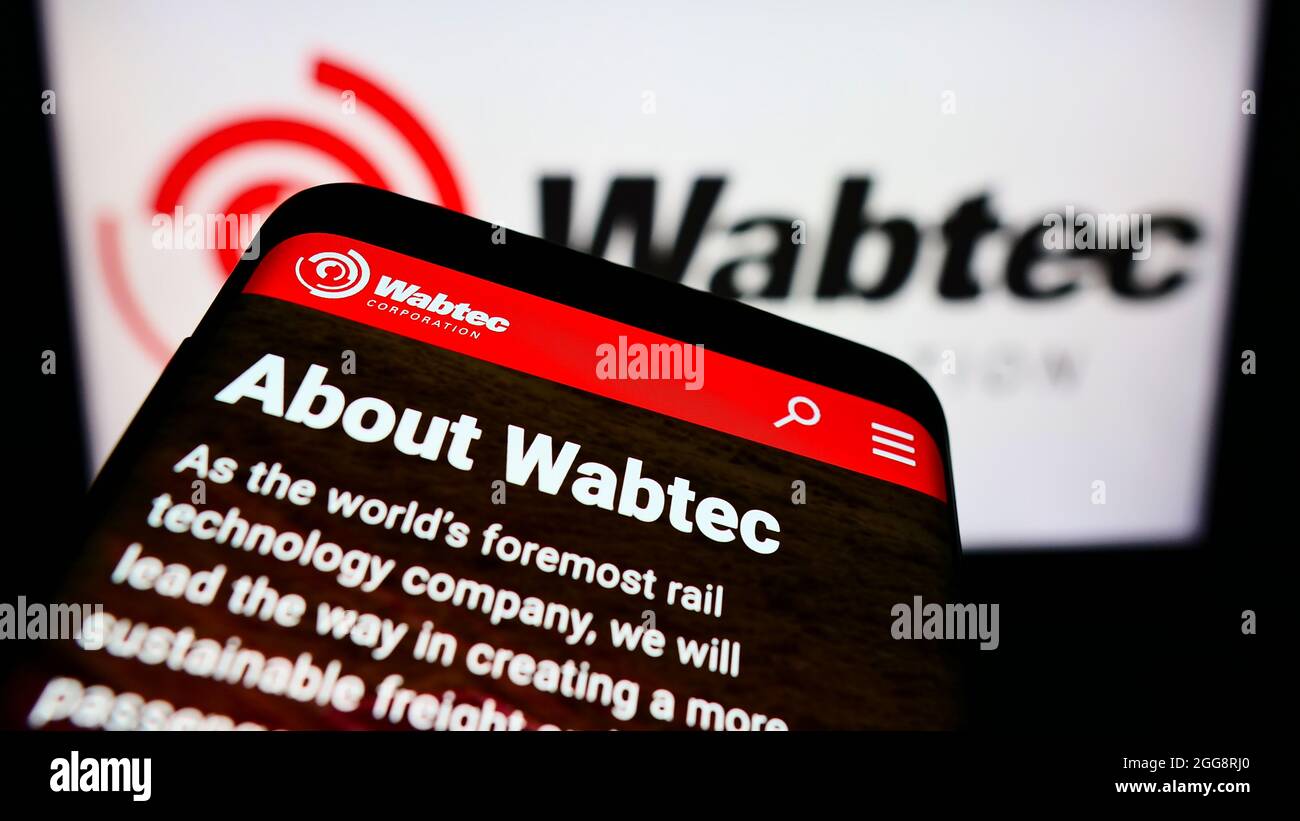 Mobile phone with website of US rail manufacturer Wabtec Corporation on screen in front of business logo. Focus on top-left of phone display. Stock Photo