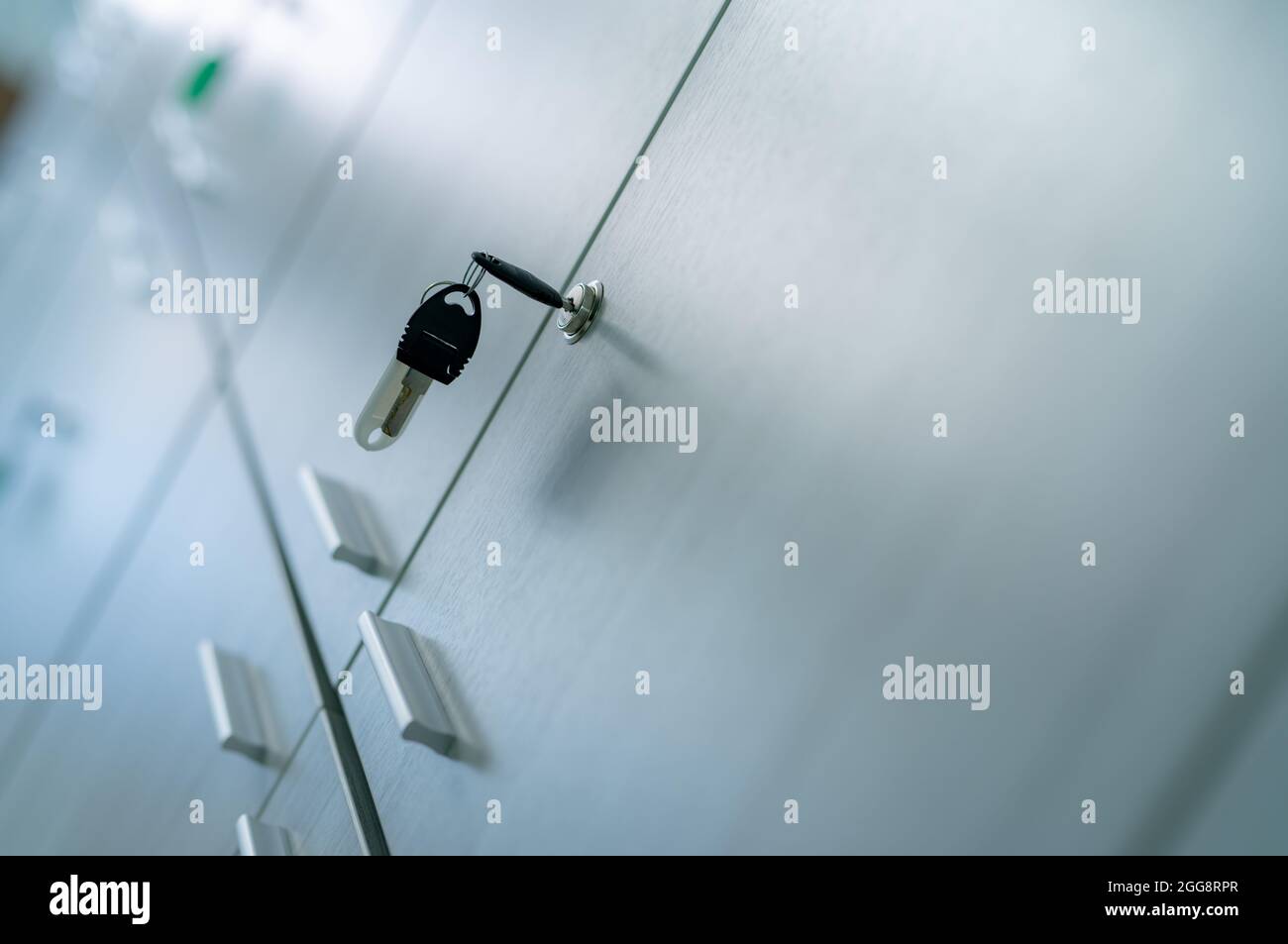 Locker with key in office room. Filing cabinet lock with key for safety and security system in public facility. Secure lock system for document files Stock Photo