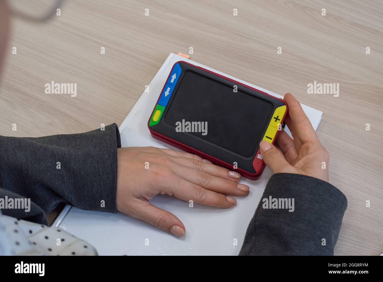 The woman is holding a reading device for the visually impaired