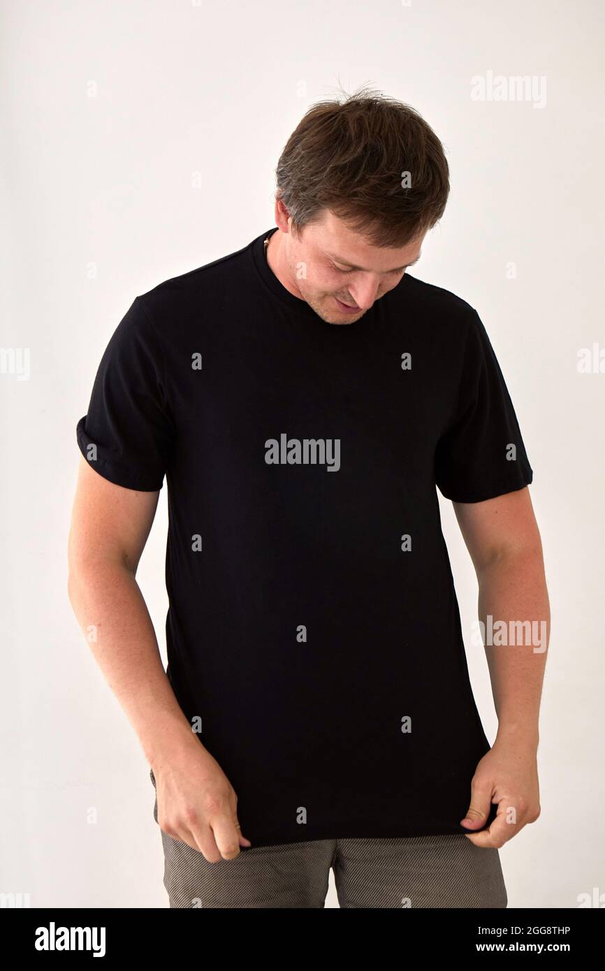 Young male model wearing basic black t shirt with space for print standing against white background Stock Photo