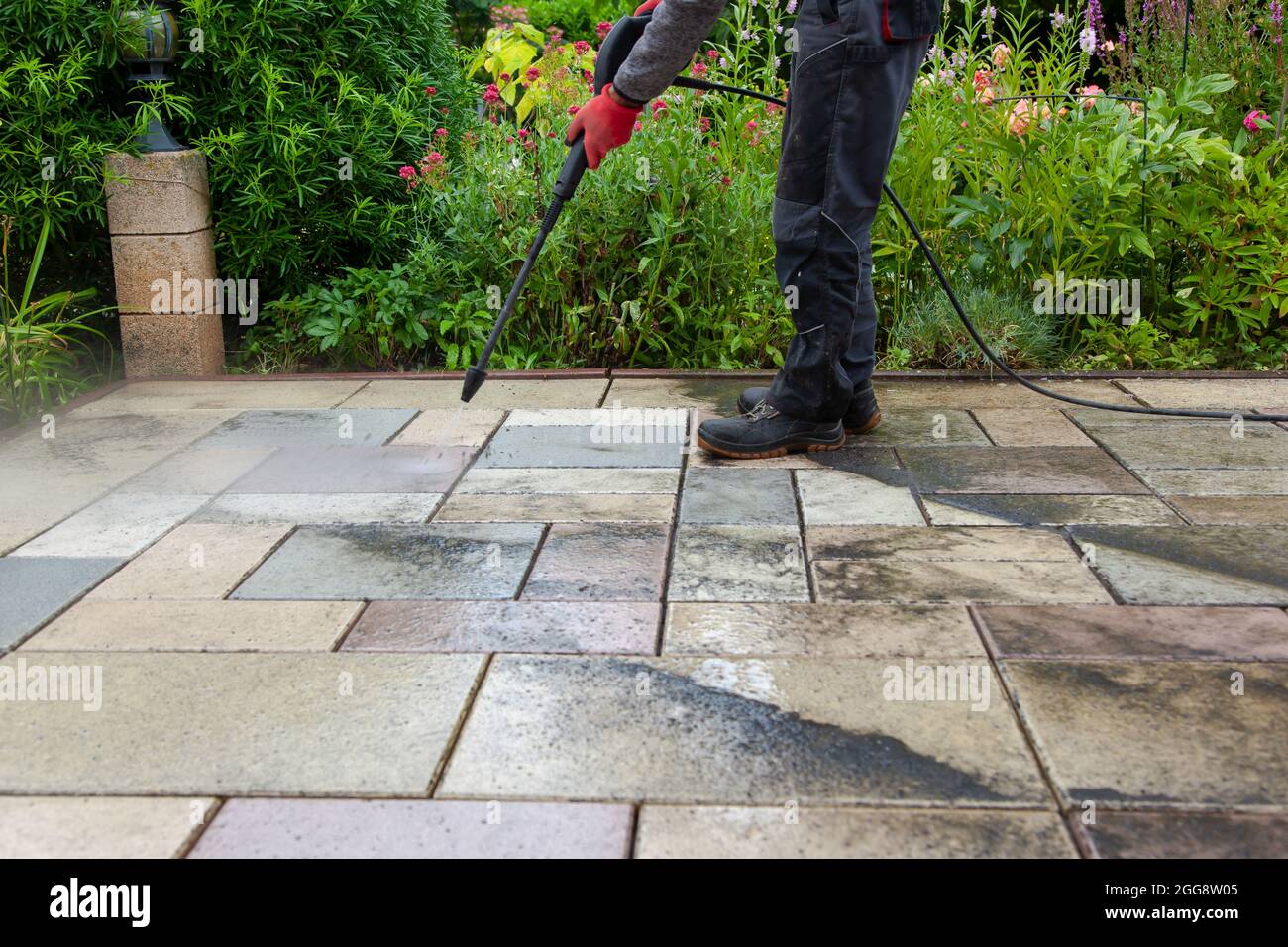 Cleaning stone slabs on patio with the highpressure cleaner. Person