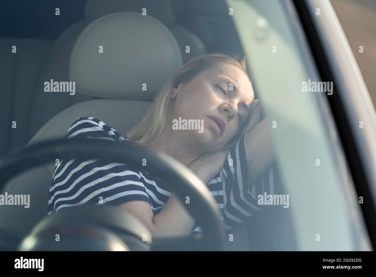 Woman tired of driving sleep on front seat. Female travel by car on road trip resting napping inside Stock Photo