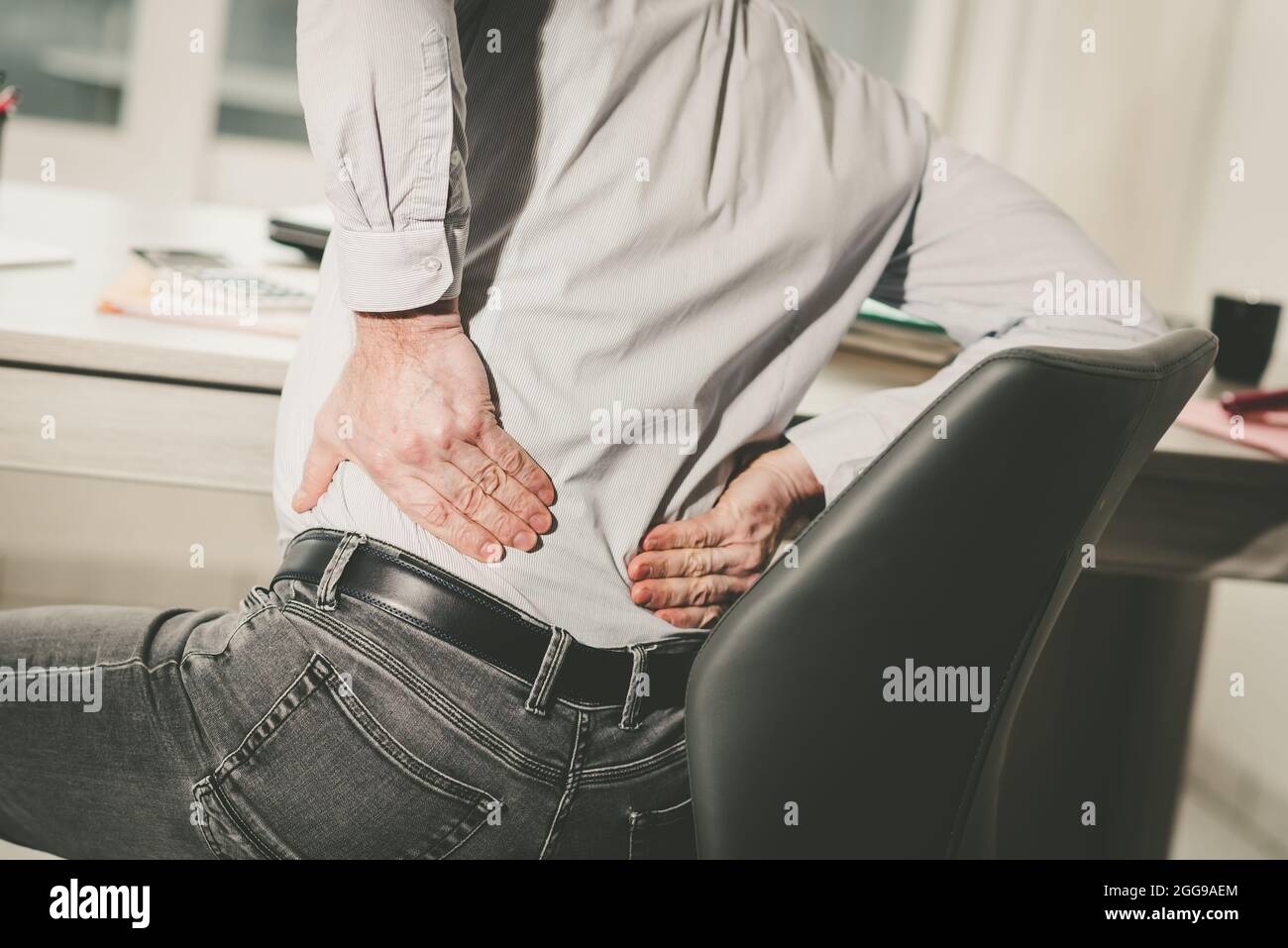 Businessman suffering from back pain in office, light effect Stock ...