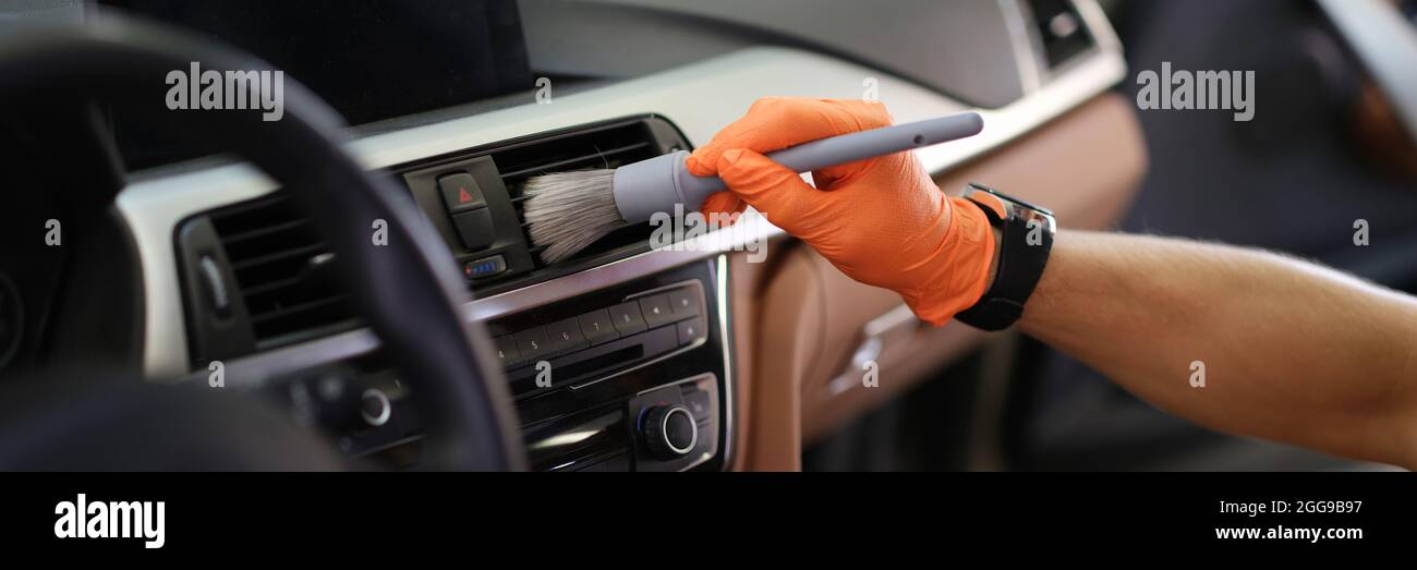 Male hand hold grey blush in orange protective gloves Stock Photo
