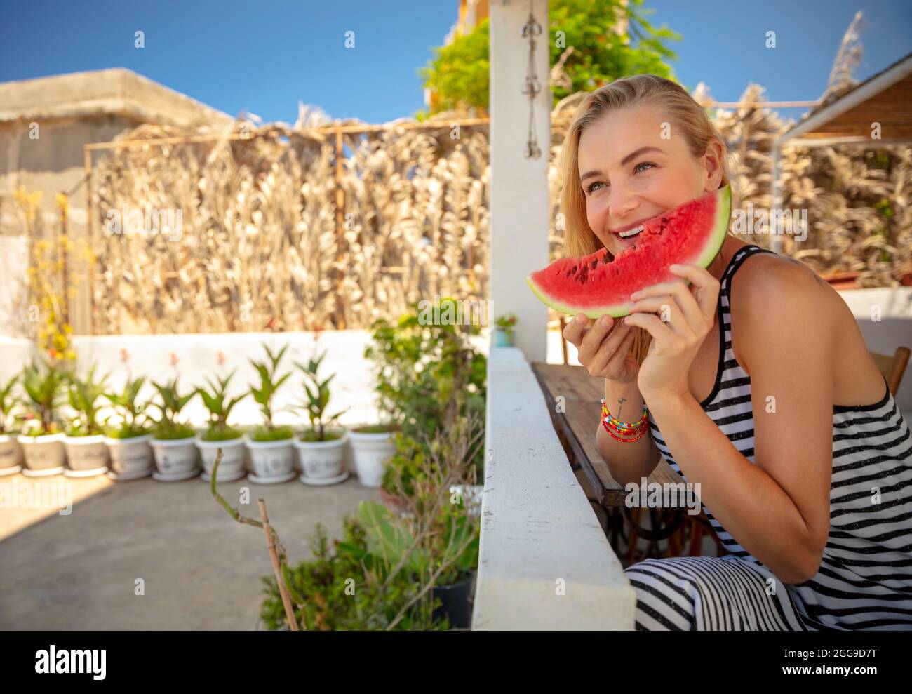 Pretty Girl with Pleasure Eating Ripe Fresh Juicy Watermelon. Enjoying Tasty Sweet Summertime Fruits. Enjoying Beach House. Happy Summer Vacation. Stock Photo