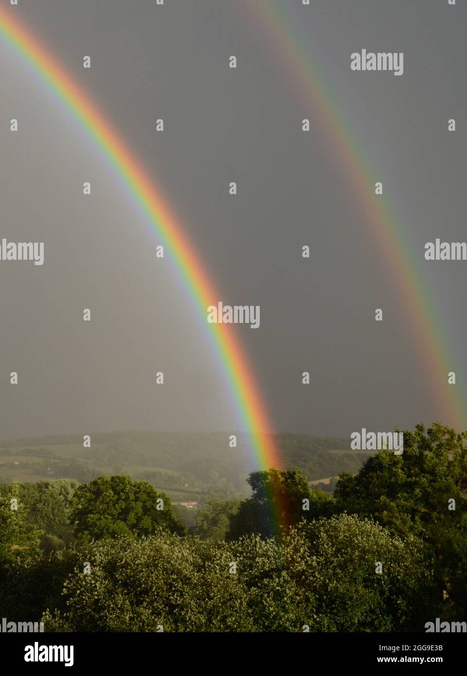 Attractive rainbow display during a summer shower shortly before sunset, viewed from Bradninch in Devon Stock Photo