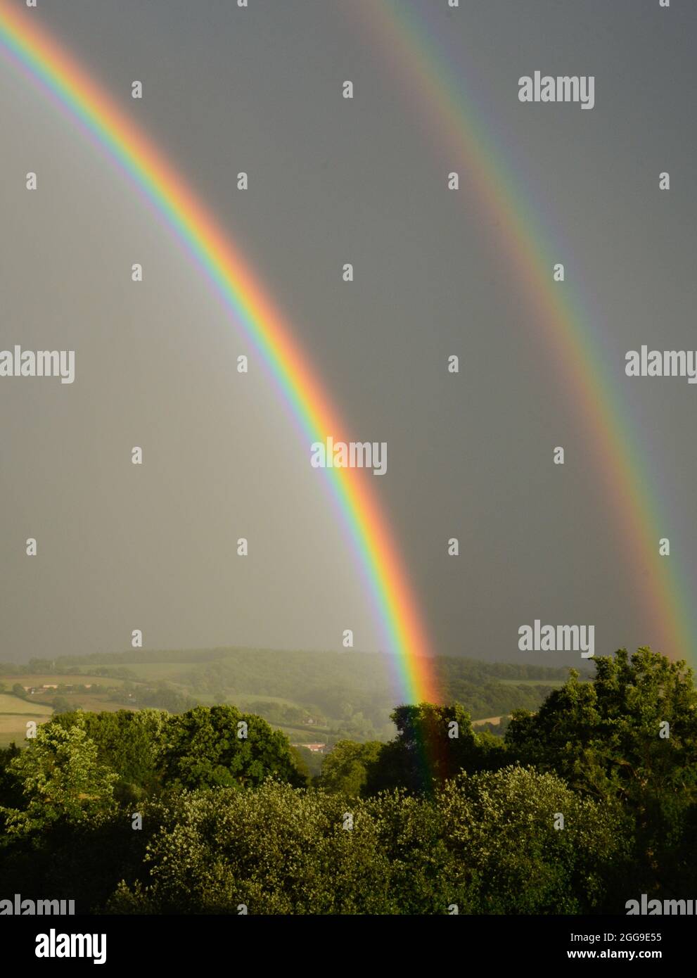 Attractive rainbow display during a summer shower shortly before sunset, viewed from Bradninch in Devon Stock Photo