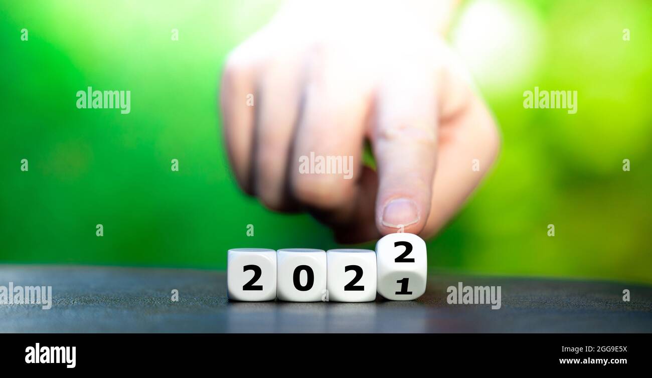 Hand turns a dice and changes the year '2021' to '2022'. Stock Photo