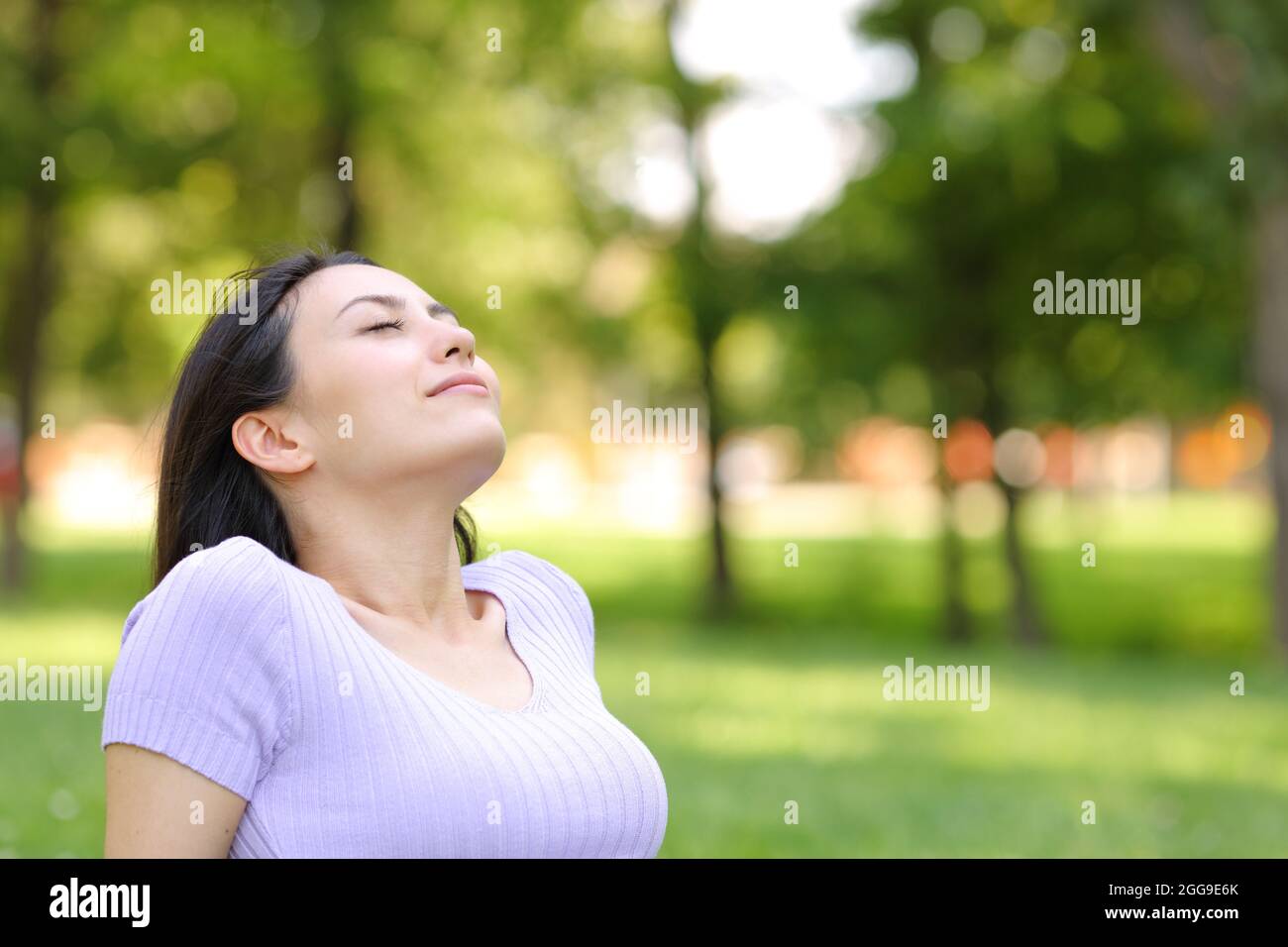 Relaxed asian woman breathing fresh air sitting in a park Stock Photo ...