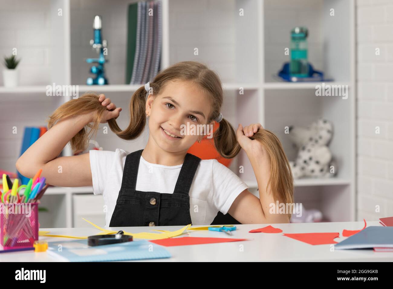 cheerful child having fun with long hair pony tail at school lesson ...