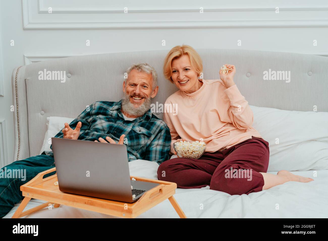 Husband and wife watch a film on the bed and eat popcorn Stock Photo Alamy