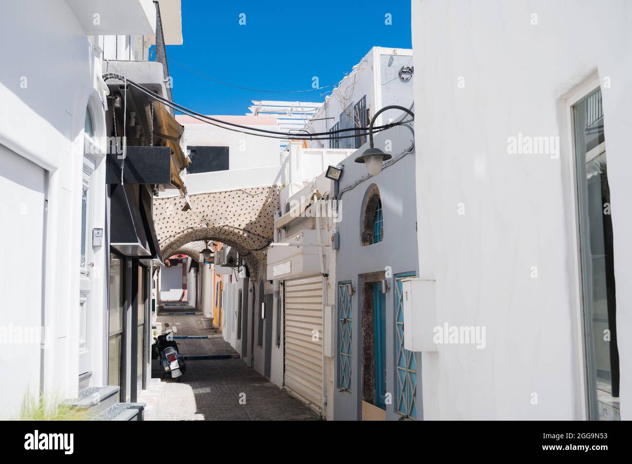 Empty narrow street in Thira, Santorini island. Closed shops during coronavirus lockdown. White greek architecture/ Stock Photo