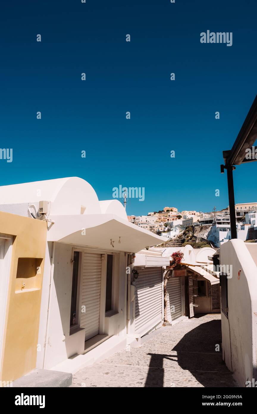 Empty narrow street in Thira, Santorini island. Closed shops during coronavirus lockdown. White greek architecture/ Stock Photo