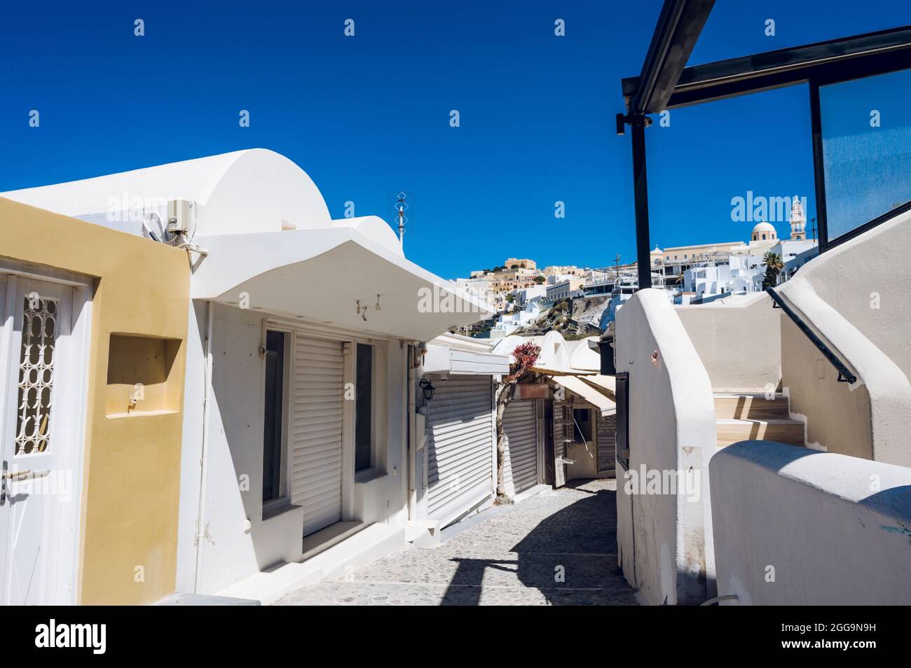 Empty narrow street in Thira, Santorini island. Closed shops during coronavirus lockdown. White greek architecture/ Stock Photo