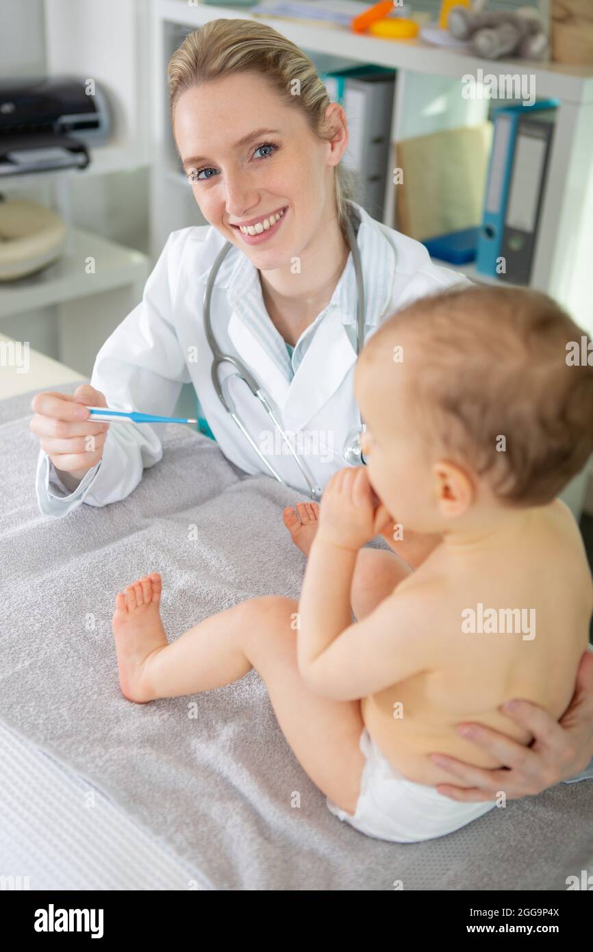 female paediatrician with baby holding a thermometer Stock Photo