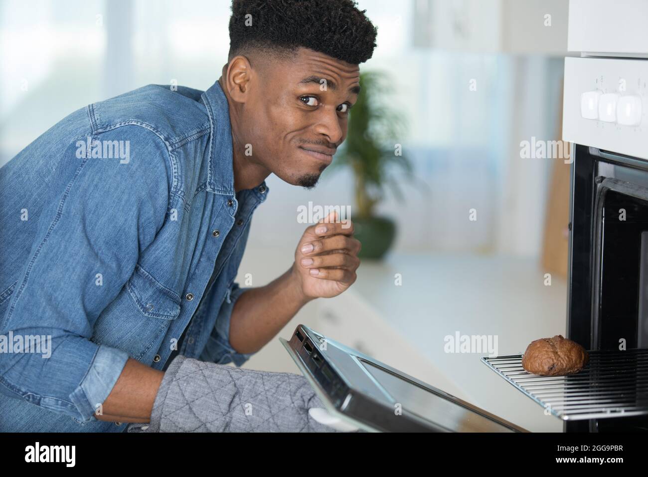 man is removing a burnt cake from the oven Stock Photo