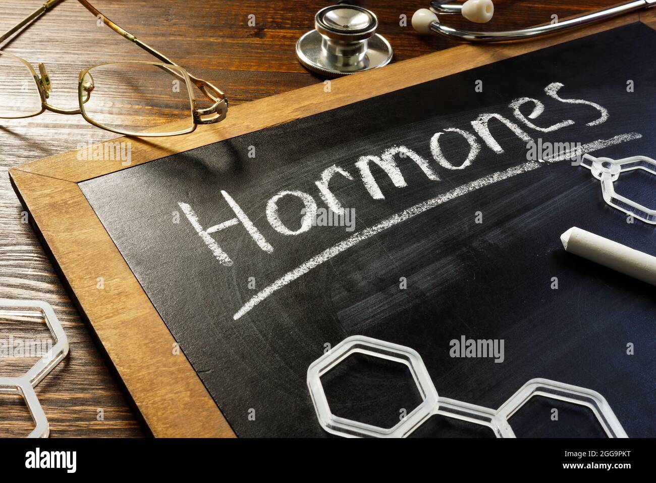 Handwritten word hormones on the blackboard and glasses. Stock Photo