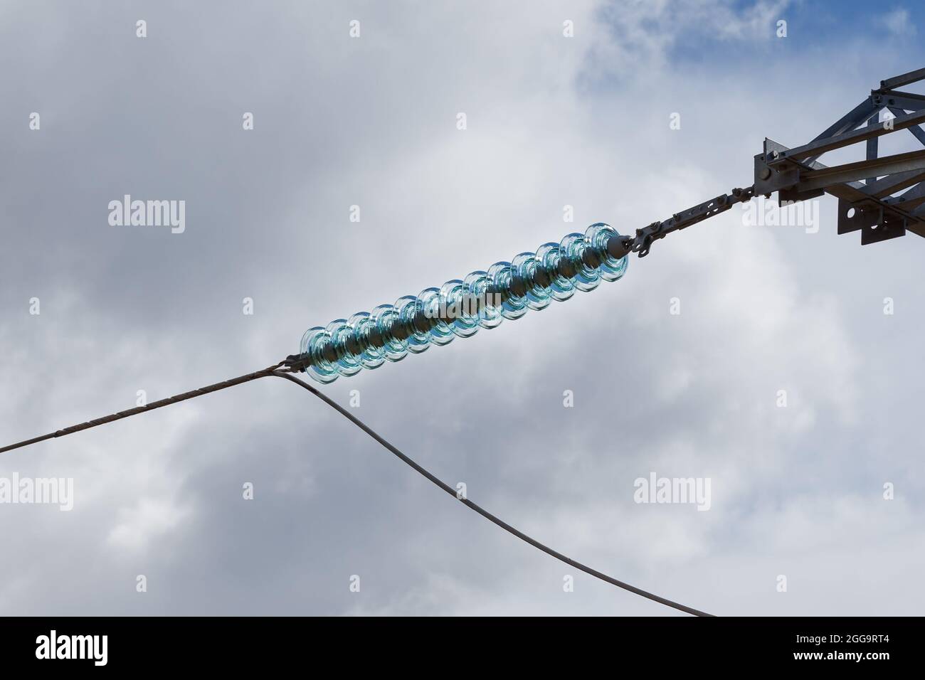 Glass insulator on high voltage power line against blue sky Stock Photo