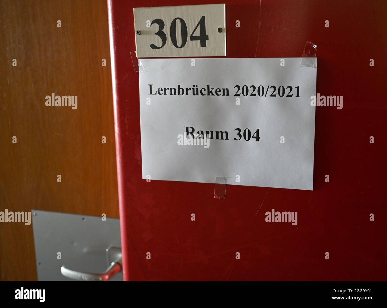 Sindelfingen, Germany. 30th Aug, 2021. A sign reading 'Learning Bridges 2020/2021 Room 304' hangs in front of a classroom at the Realschule am Goldberg. According to the Ministry of Education, around 54,000 pupils take part in so-called learning bridges at around 1900 locations in Baden-Württemberg. During the two remaining holiday weeks, around 6,200 teachers look after pupils who are to close their corona-related gaps in knowledge. Credit: Bernd Weißbrod/dpa/Alamy Live News Stock Photo