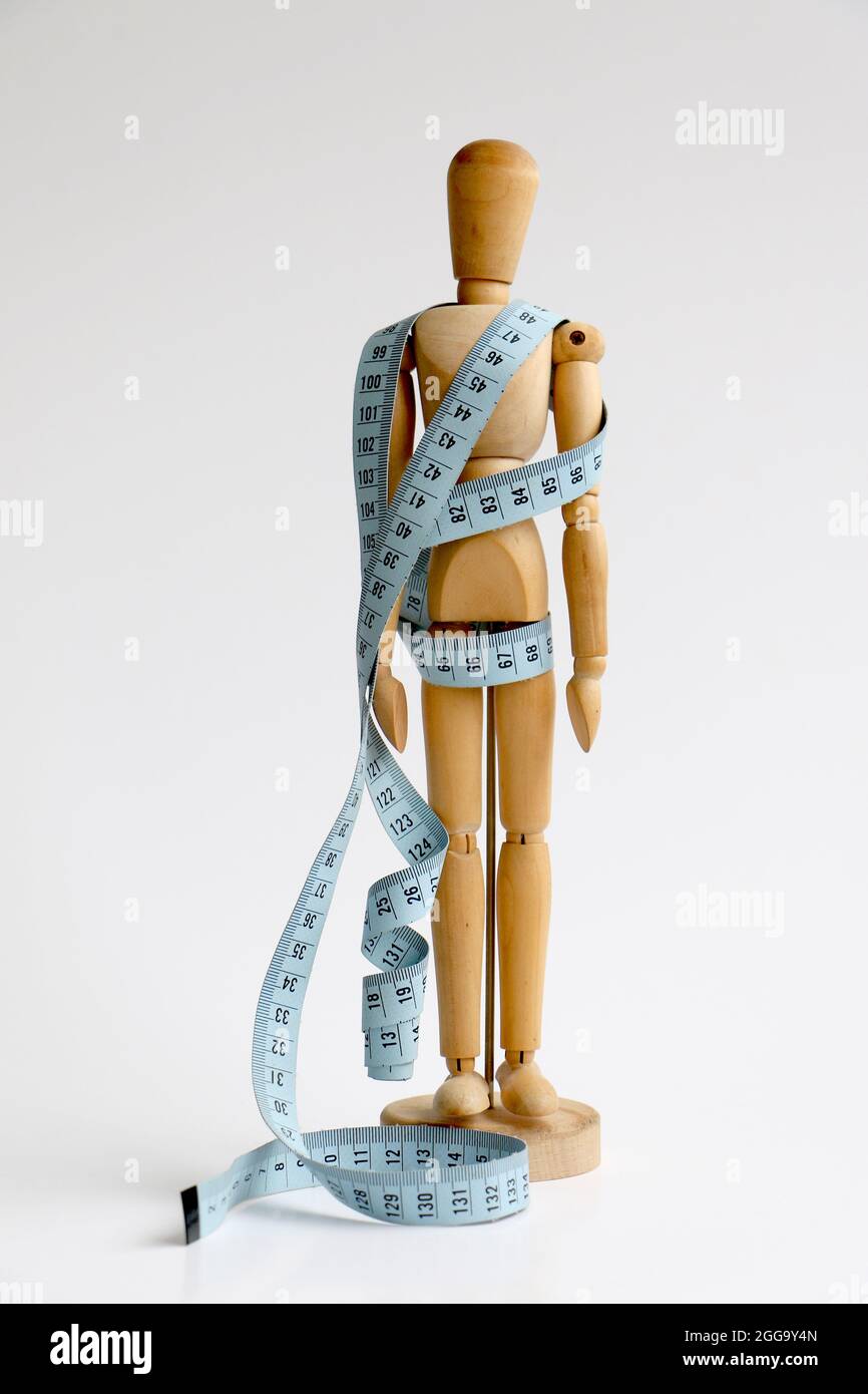 Isolated wood adjustable mannequin wrapped in a blue tape measure for a weight loss and plastic surgery beauty concept Stock Photo
