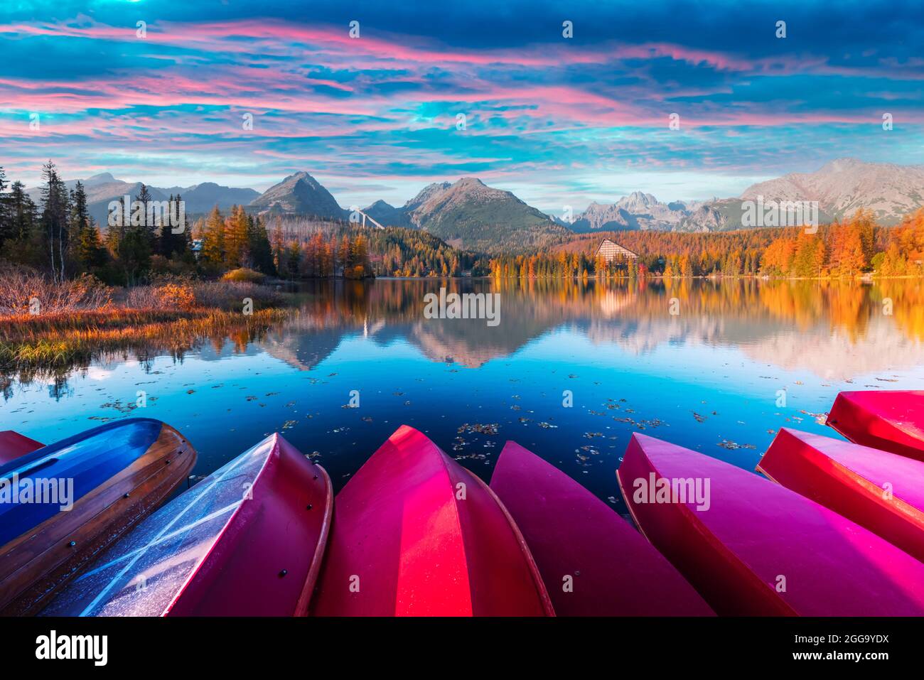 Picturesque autumn view of lake Strbske pleso in High Tatras National Park, Slovakia. Row of red wooden boats and high mountains on background. Landscape photography Stock Photo