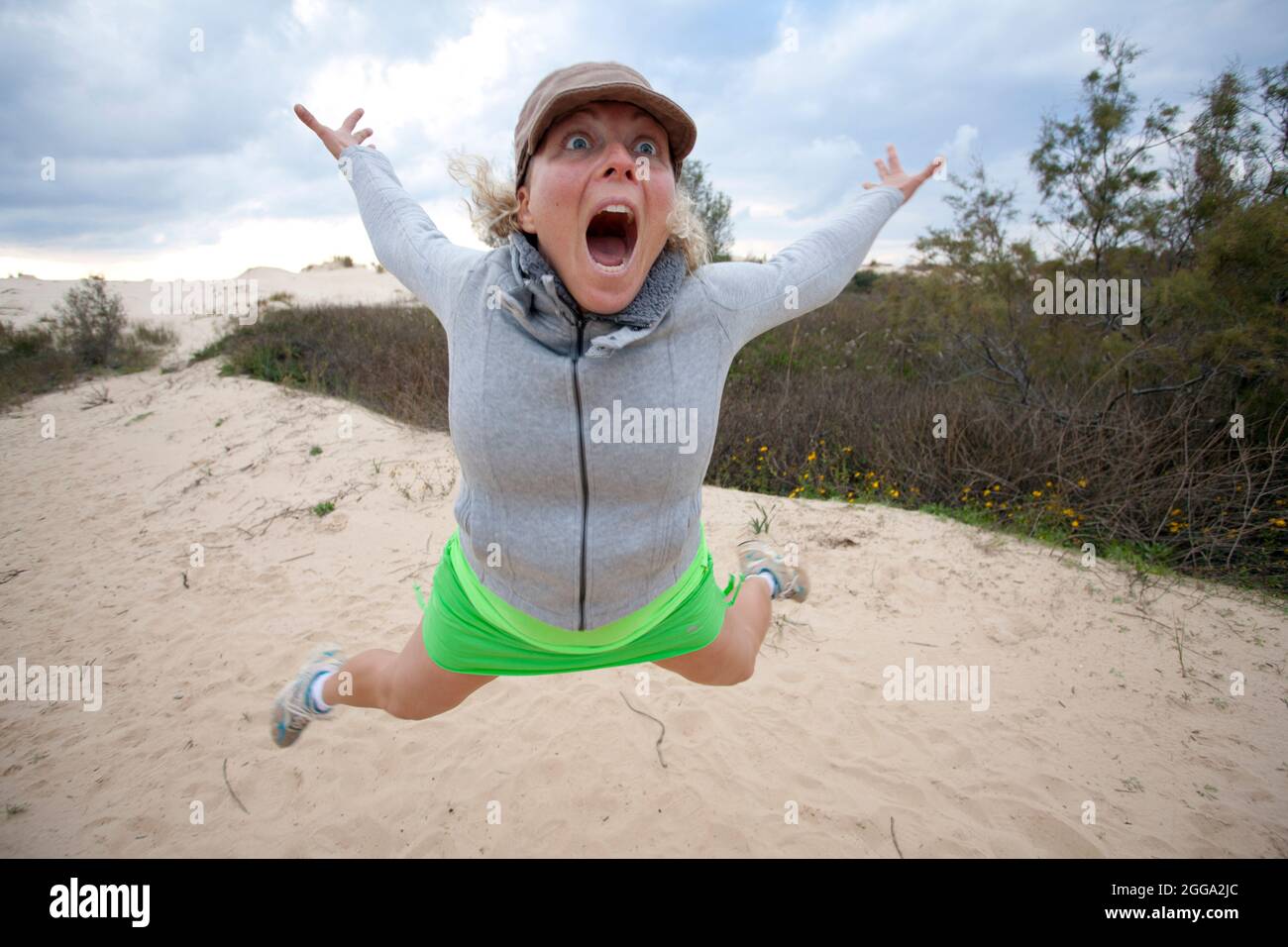 Young woman pulls a face while jumping in the air Stock Photo