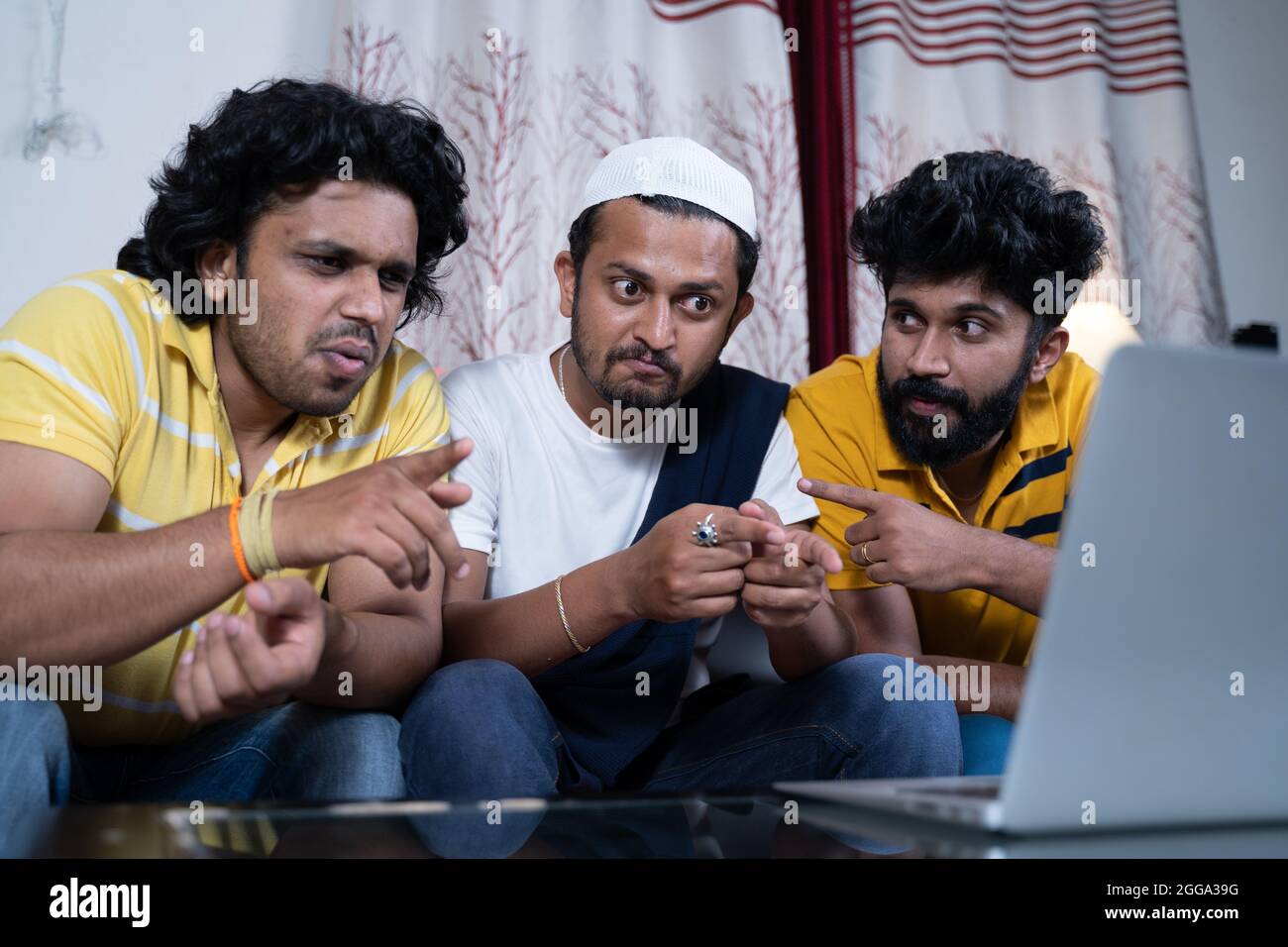 Group of multi ethnic Indian friends busy discussing while watching live streaming movie, sports match or political news at laptop Stock Photo