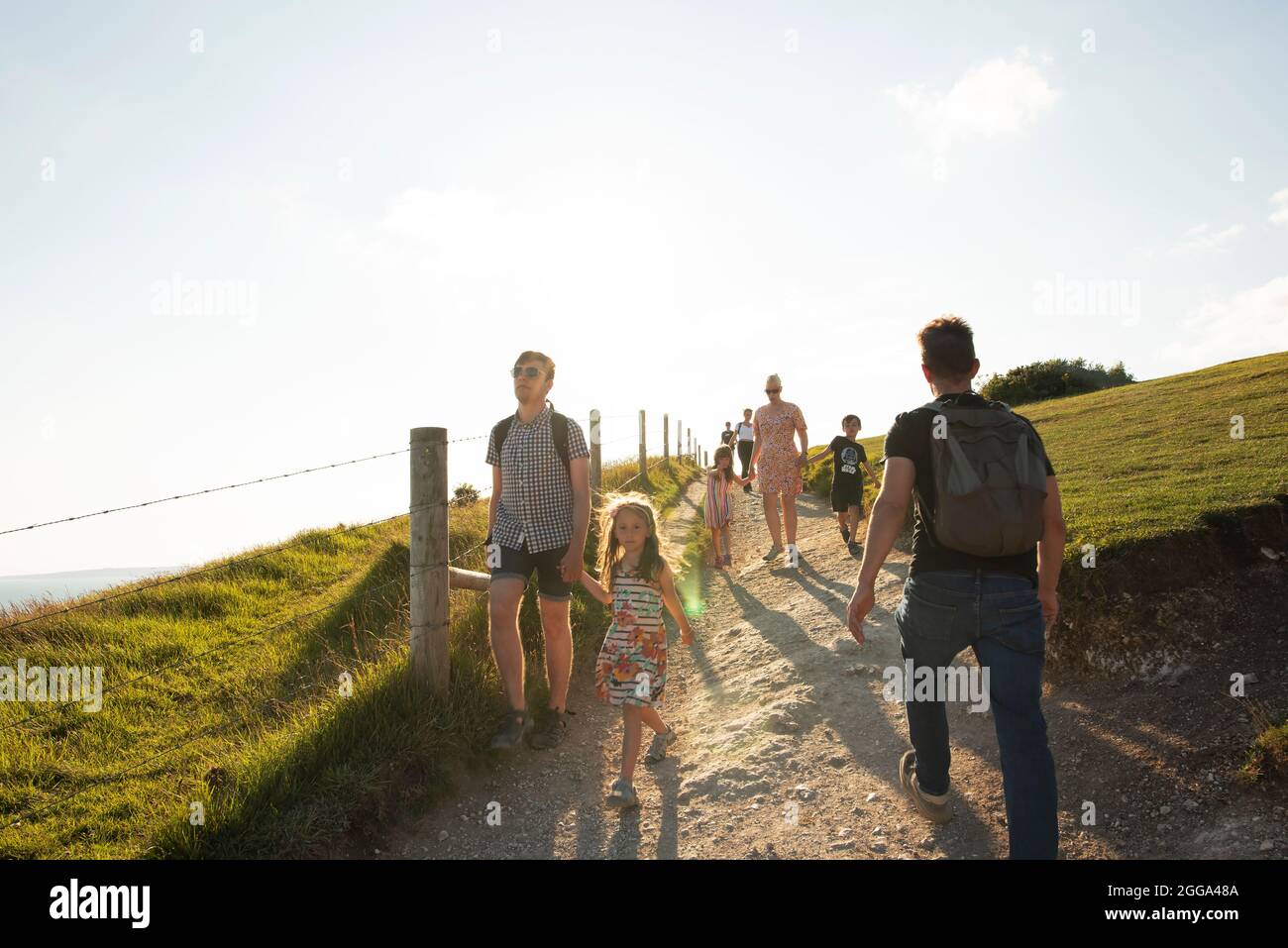 People walking down the footpath to Lulworth Cove, the Jurassic Coast’s  iconic landscape. Dorset, UK. Aug 2021 Stock Photo