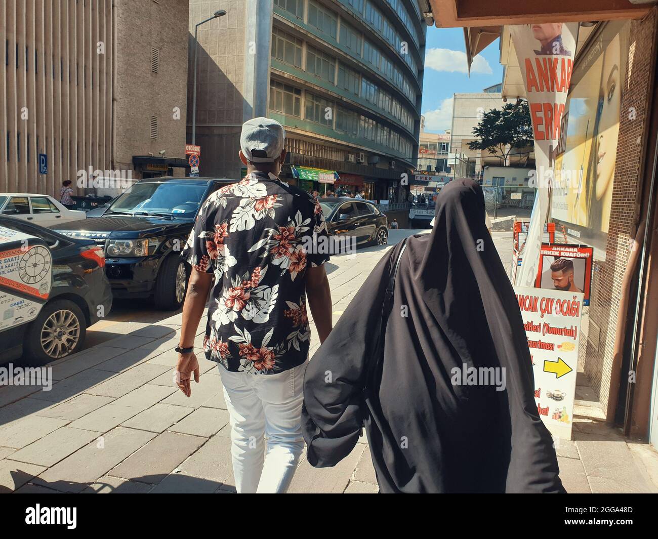 Man in sportswear and woman in hijab walking in Anafartalar Street in the Ulus district in Ankara, Turkey. Stock Photo