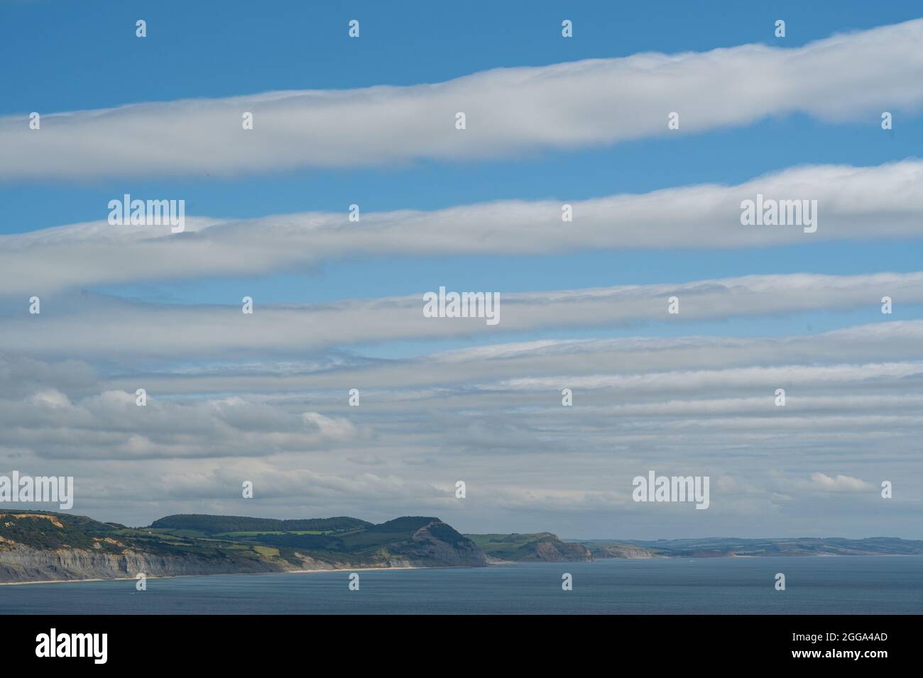 Lyme Regis, Dorset, UK. 30th Aug, 2021. UK Weather: Clouds clear over the Jurassic coast and Lyme Regis creating stripes in the sky. Credit: Celia McMahon/Alamy Live News Stock Photo