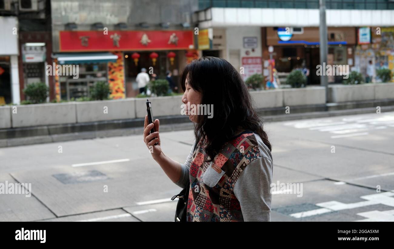 Chinese lady doing a selfie Nathan Road is the main Passage Way in Yau Ma Tai, Mongkok, Kowloon, Hong Kong, China Stock Photo