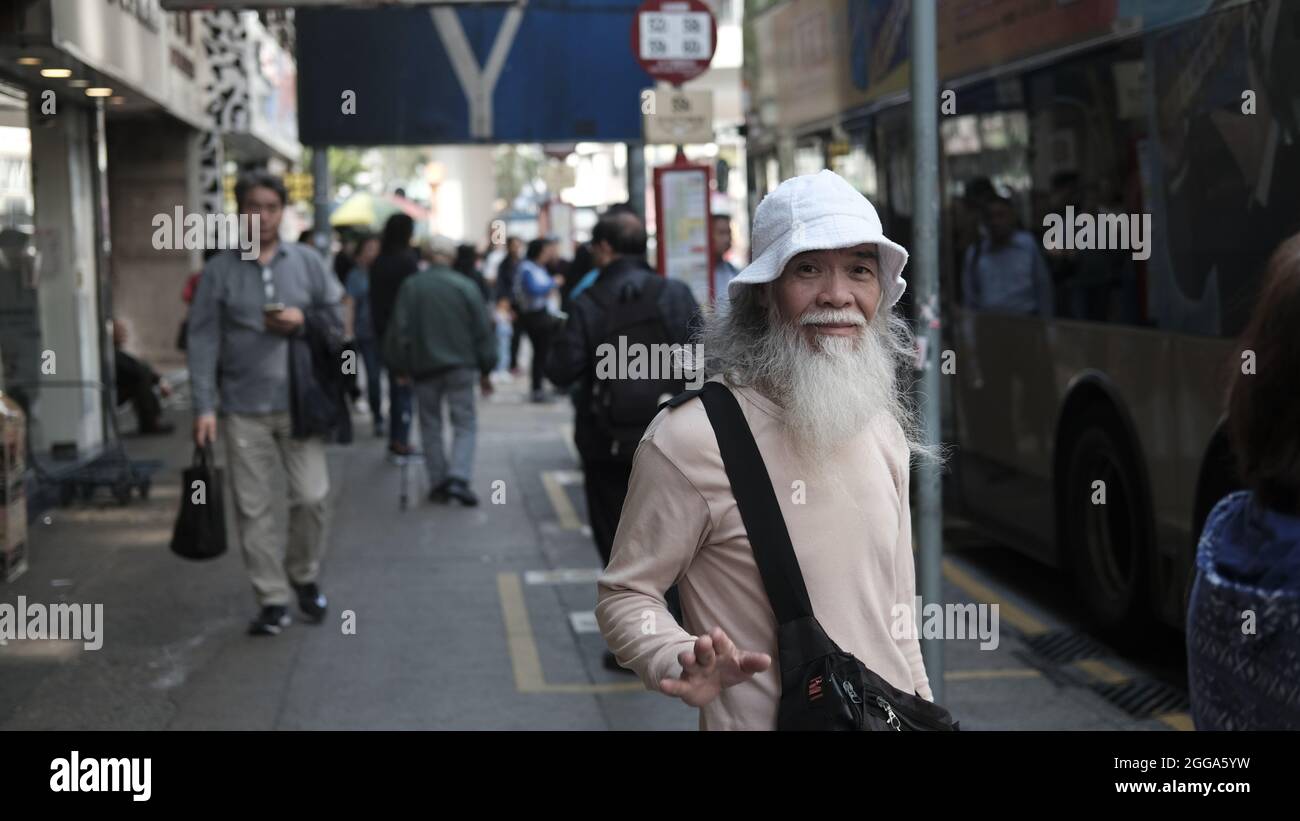 Old Chinese Man Pedestrian with Long White Beard Nathan Road is the main Passage Way in Yau Ma Tai, Mongkok, Kowloon, Hong Kong, China Stock Photo