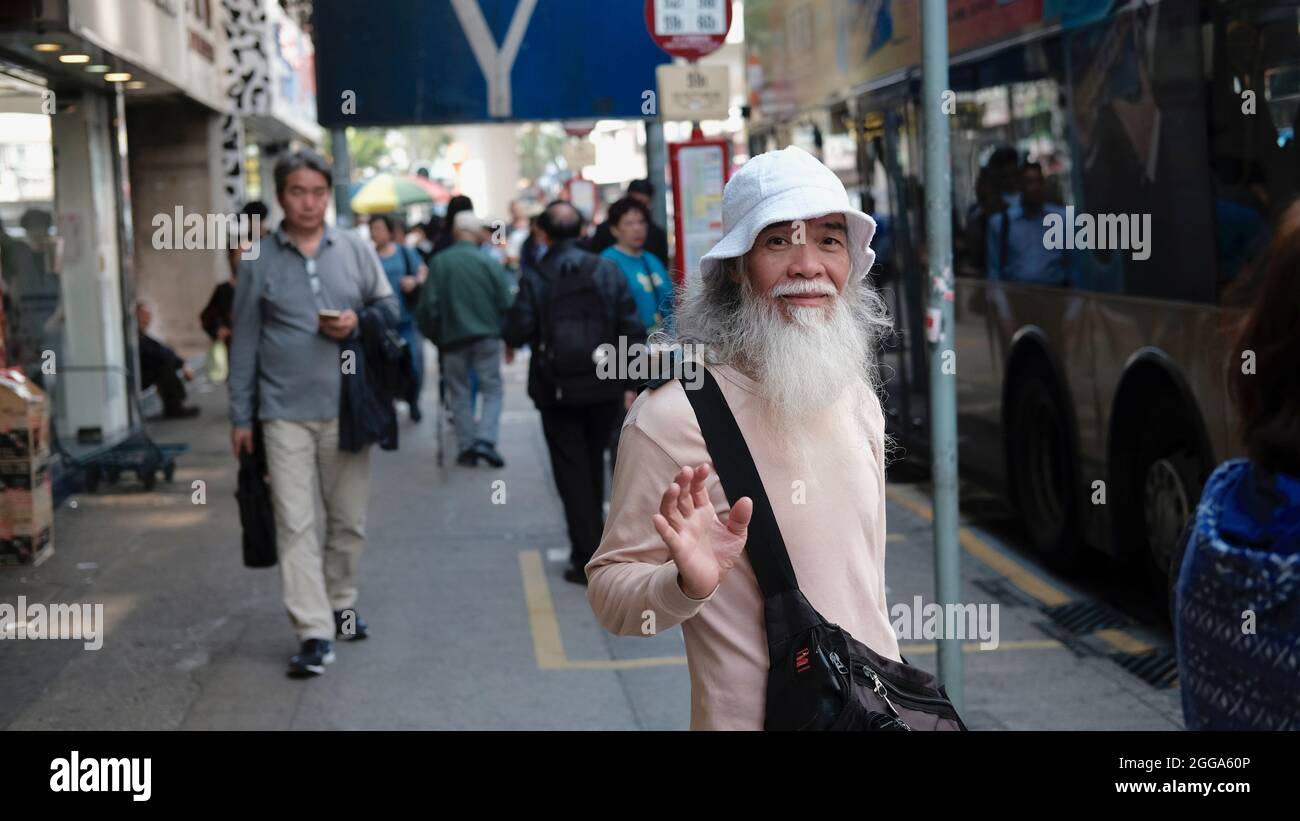 Old Chinese Man Pedestrian with Long White Beard Nathan Road is the main Passage Way in Yau Ma Tai, Mongkok, Kowloon, Hong Kong, China Stock Photo