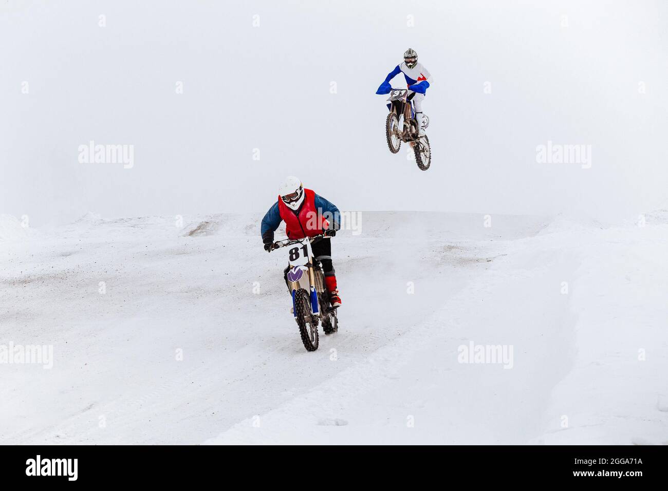 two motorcyclists riding winter enduro race on snow Stock Photo