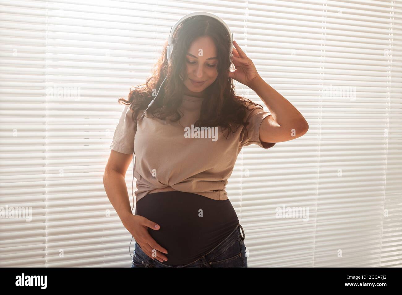 Music and pregnancy. Expectant woman holding headphones near belly Stock  Photo - Alamy