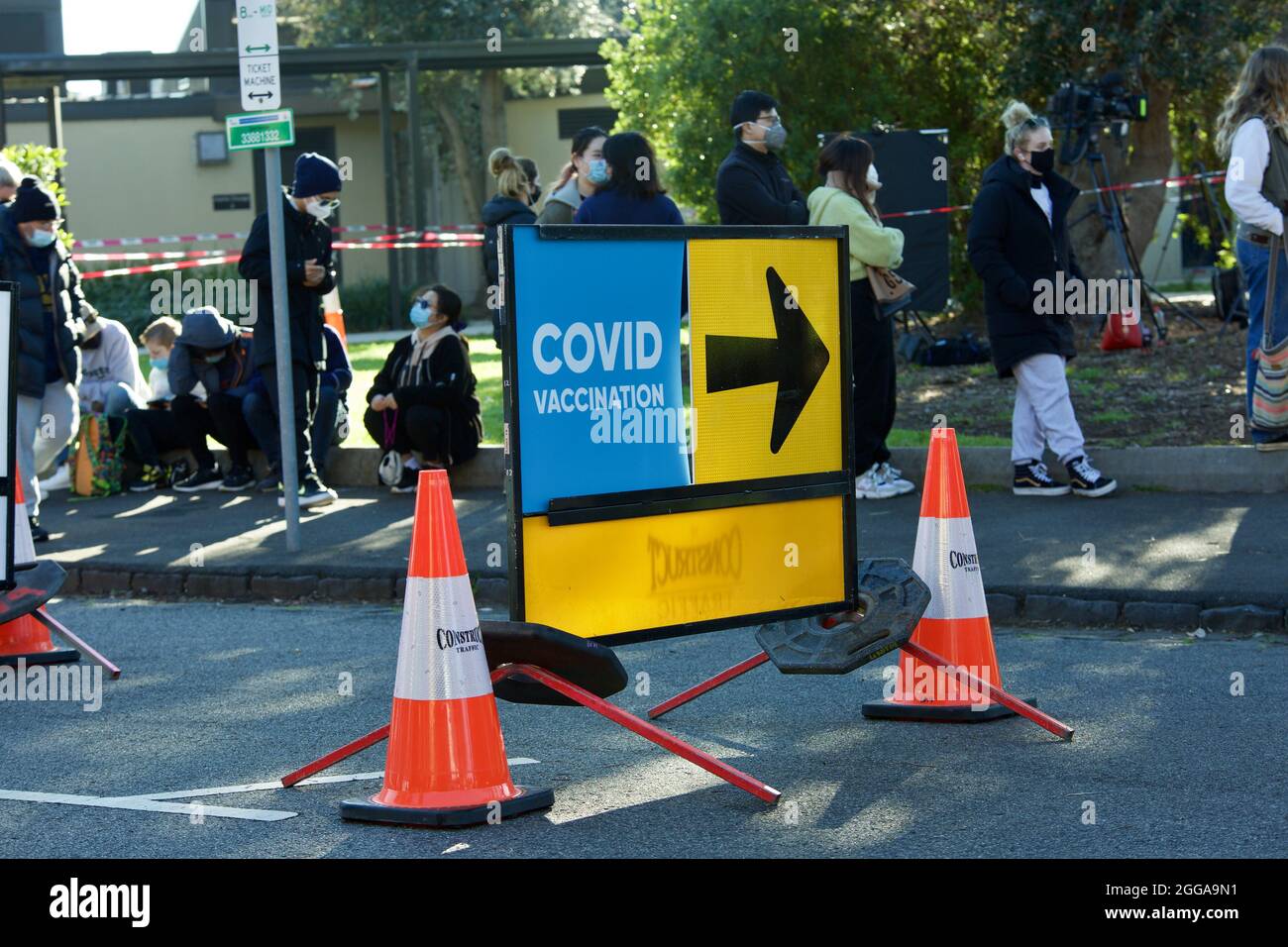 MELBOURNE, AUSTRALIA - Aug 28, 2021: Covid sign and arrow with people lining up to get coronavirus vaccine at new walk-in covid-19 vaccination clinic Stock Photo