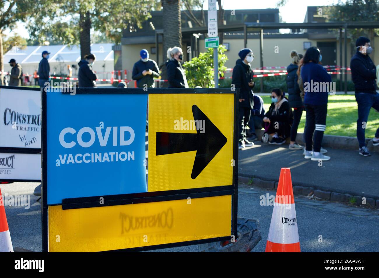 MELBOUR, AUSTRALIA - Aug 28, 2021: Covid sign and arrow with people lining up to get coronavirus vaccine at new walk-in covid-19 vaccination clinic at Stock Photo