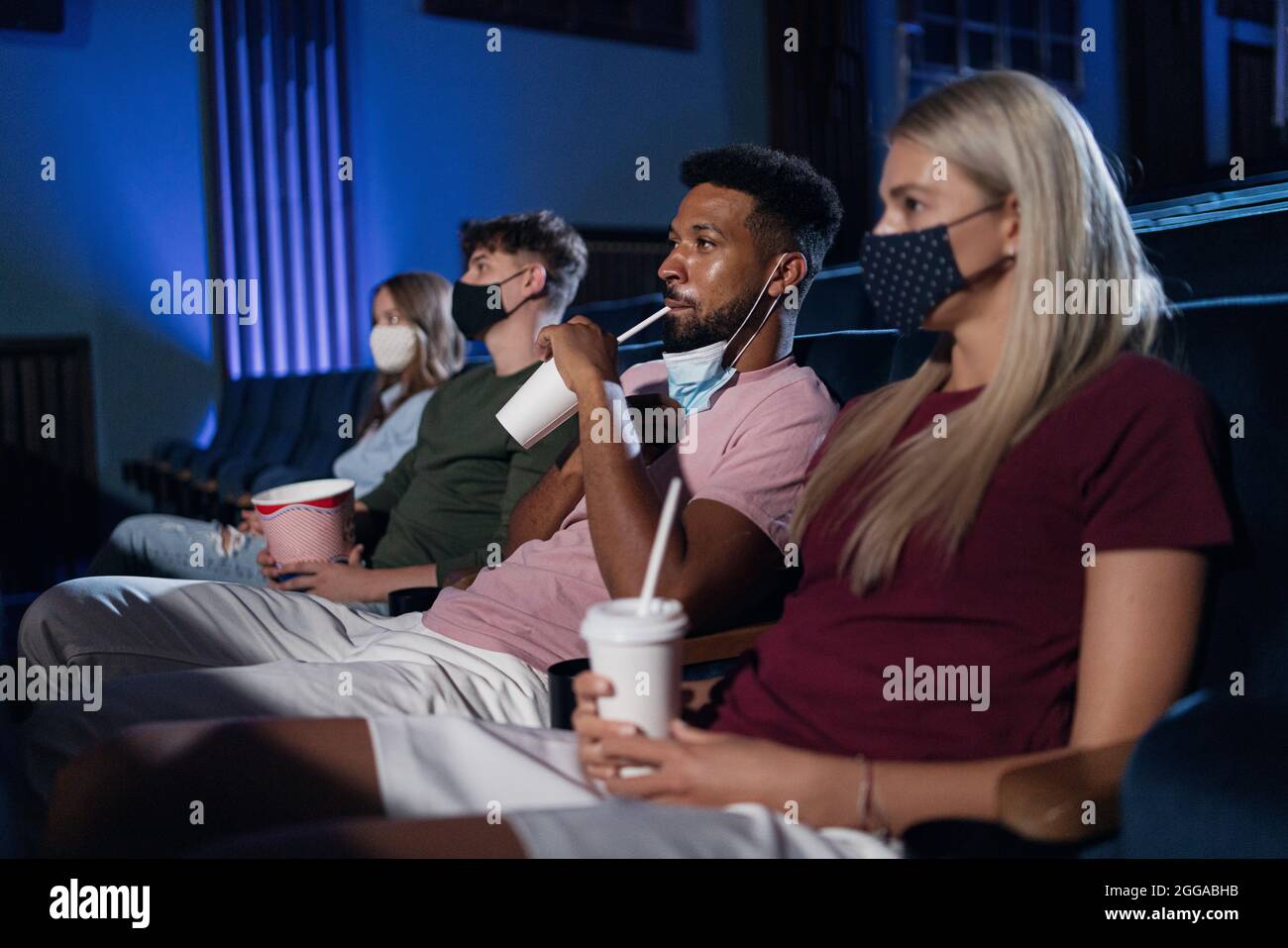 Young people watching film in the cinema, coronavirus concept. Stock Photo