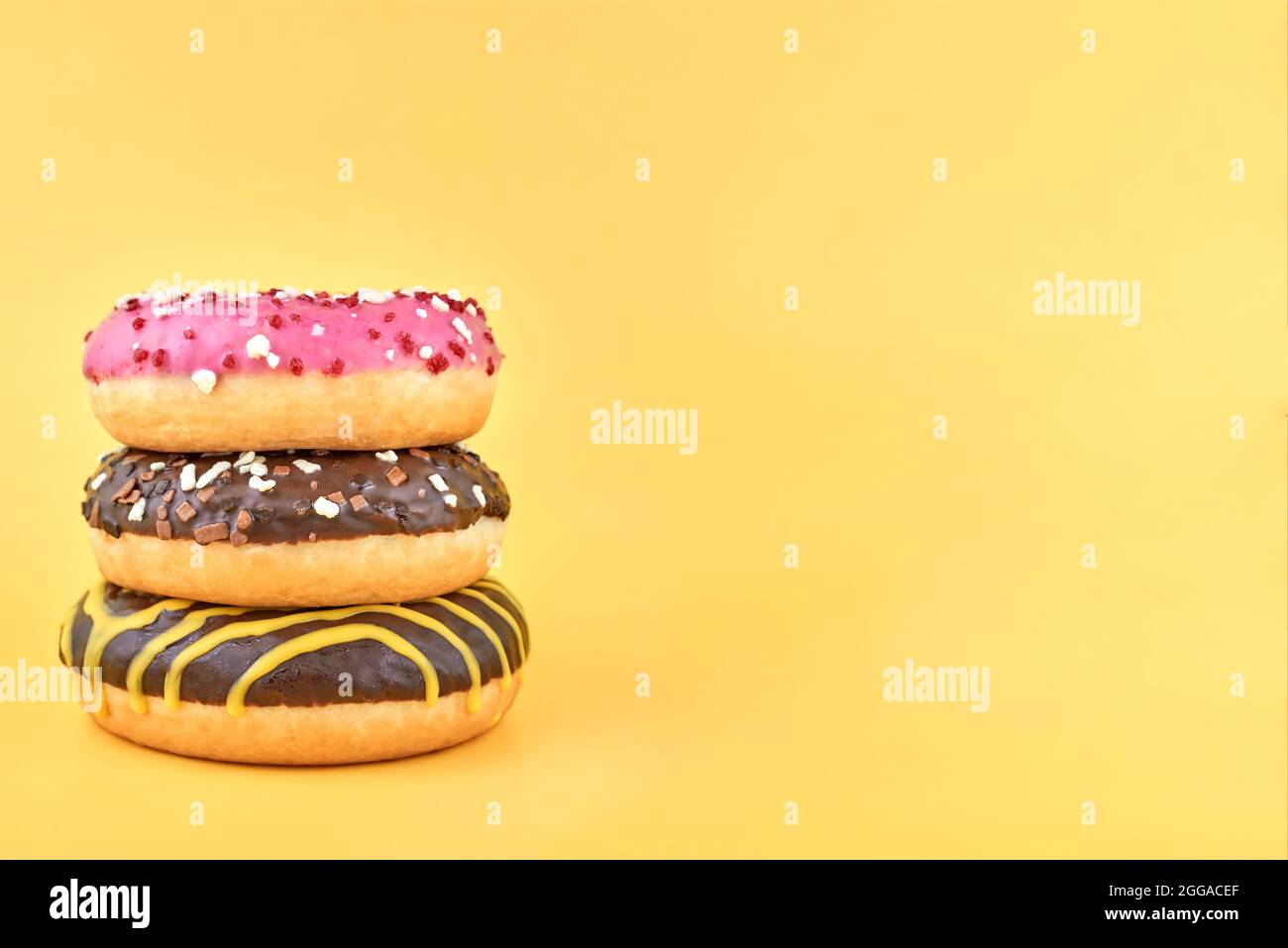 Three bright donuts on a yellow background. Stock Photo