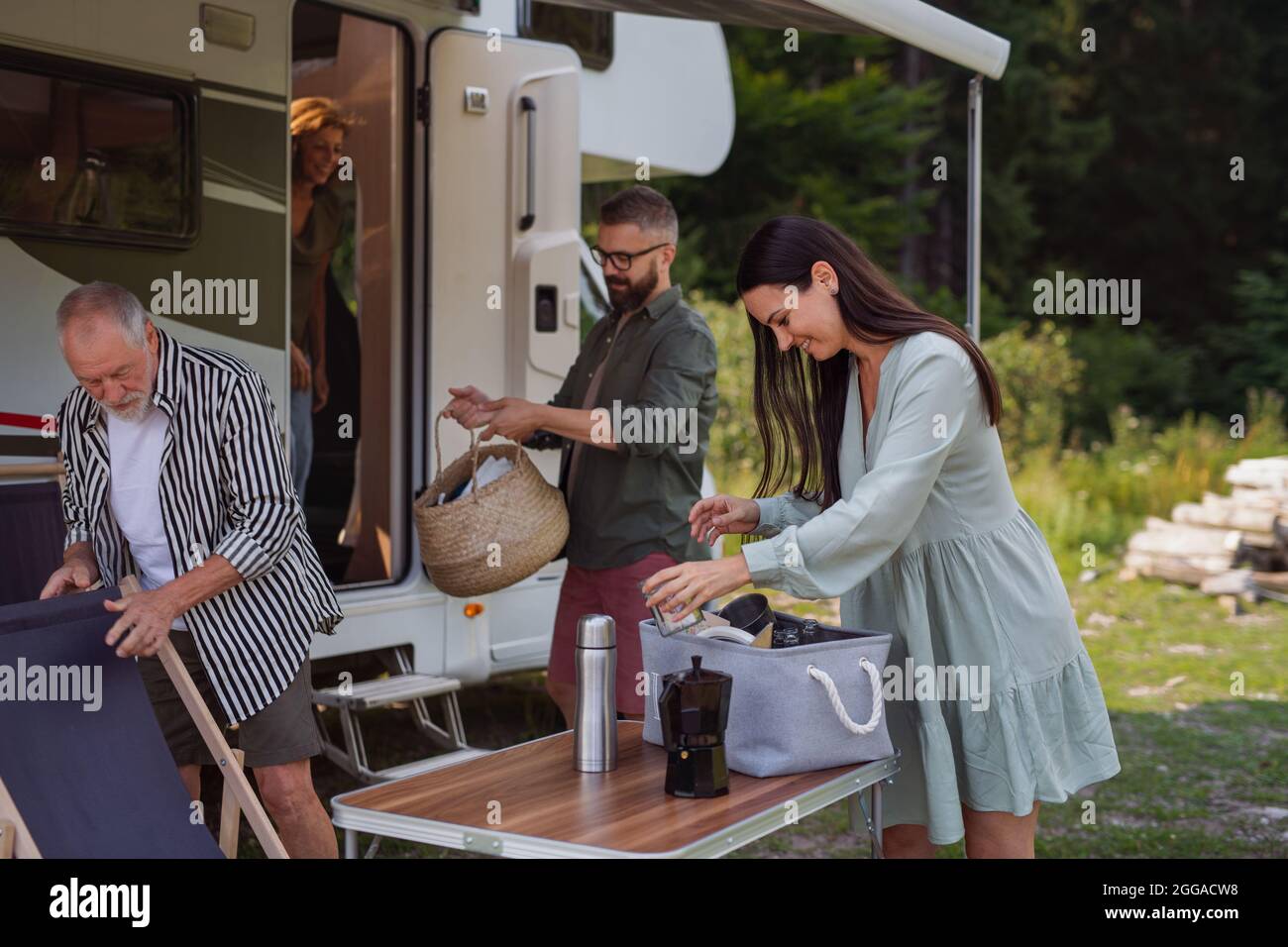 Multi-generation family unpacking and talking by car, caravan holiday trip. Stock Photo